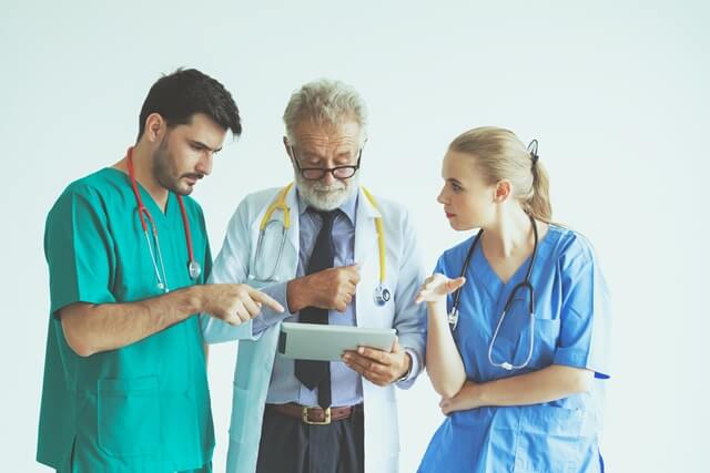 Senior doctor and two nurses looking at an ipad